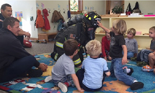 big sky firefighter with a group of children at a school