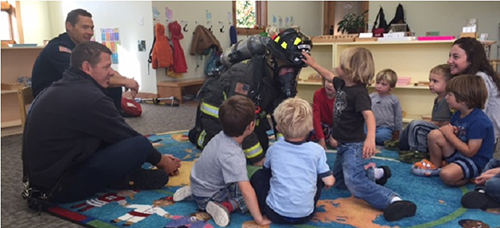 big sky firefighter with a group of children at a school